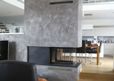 Panoramakamin in Betonoptik mit breiter Sichtscheibe und integriertem Feuertisch im modernen Wohnraum.