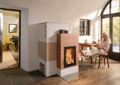 Klassischer BRUNNER Panoramakamin mit heller Verkleidung, großer Sichtscheibe und sichtbarem Feuer im Wohnraum.