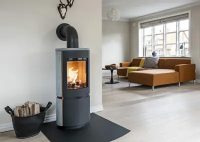 HETA Scan-Line 8 Kaminofen mit Specksteinverkleidung, großer Sichtscheibe und sichtbarem Feuer im Wohnraum.