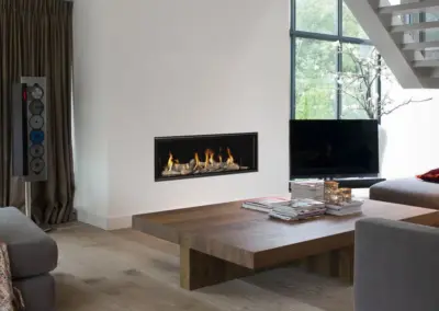Mittig im Wohnraum platzierter BRUNNER Gas-Architekturkamin mit breitem Feuerraum und gut sichtbarem Flammenspiel hinter der Scheibe.