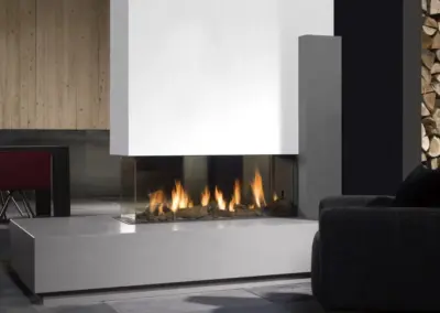 BRUNNER Gas-Panoramakamin mit breiter Feuerstelle, dunkler Verkleidung und sichtbarem Flammenspiel im Wohnraum.