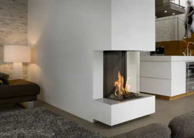 BRUNNER Gas-Panoramakamin mit Eckverglasung, heller Verkleidung und sichtbarem Feuer.