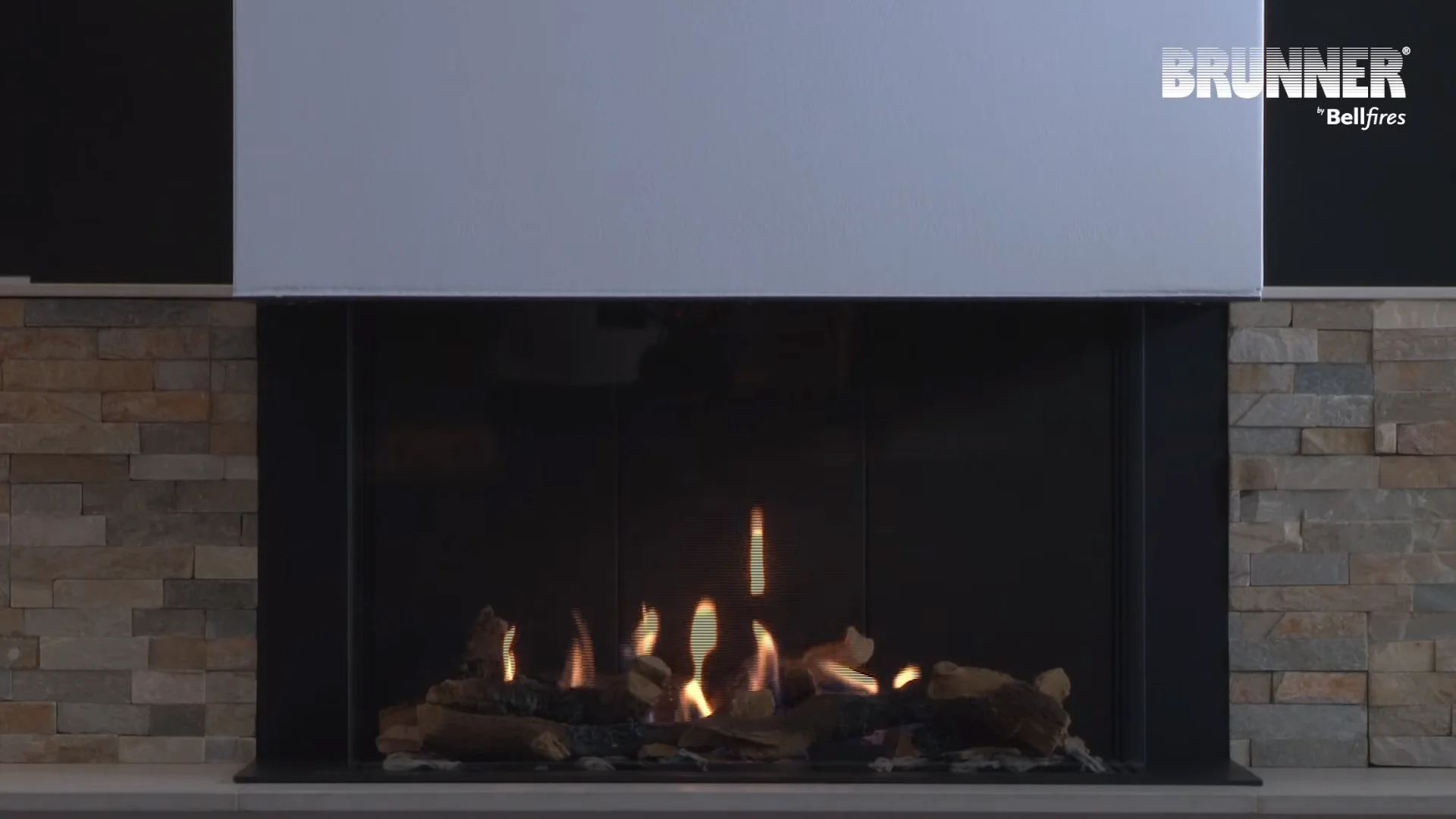 BRUNNER Gaskamin mit breitem Sichtfenster, Natursteinverkleidung und sichtbarem Flammenspiel hinter Glas.