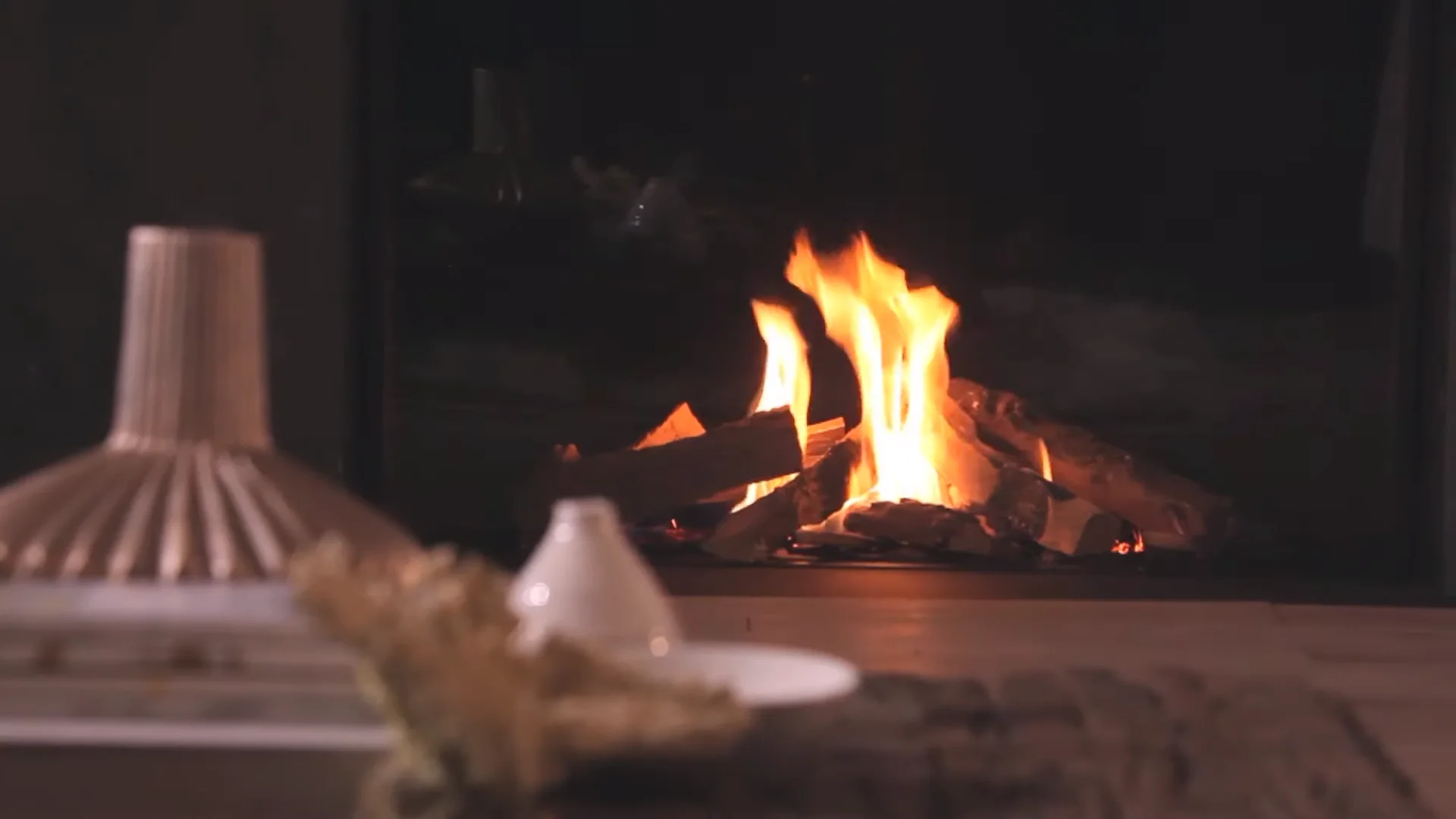 DRU Gaskamin mit breitem Feuerraum, sichtbarem Flammenspiel und dekorativer Einrichtung im Vordergrund.