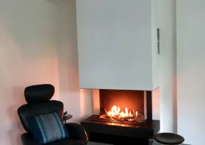 Moderner Gaskamin mit dreiseitiger Verglasung, breitem Feuerraum und sichtbarem Flammenspiel im Wohnbereich.
