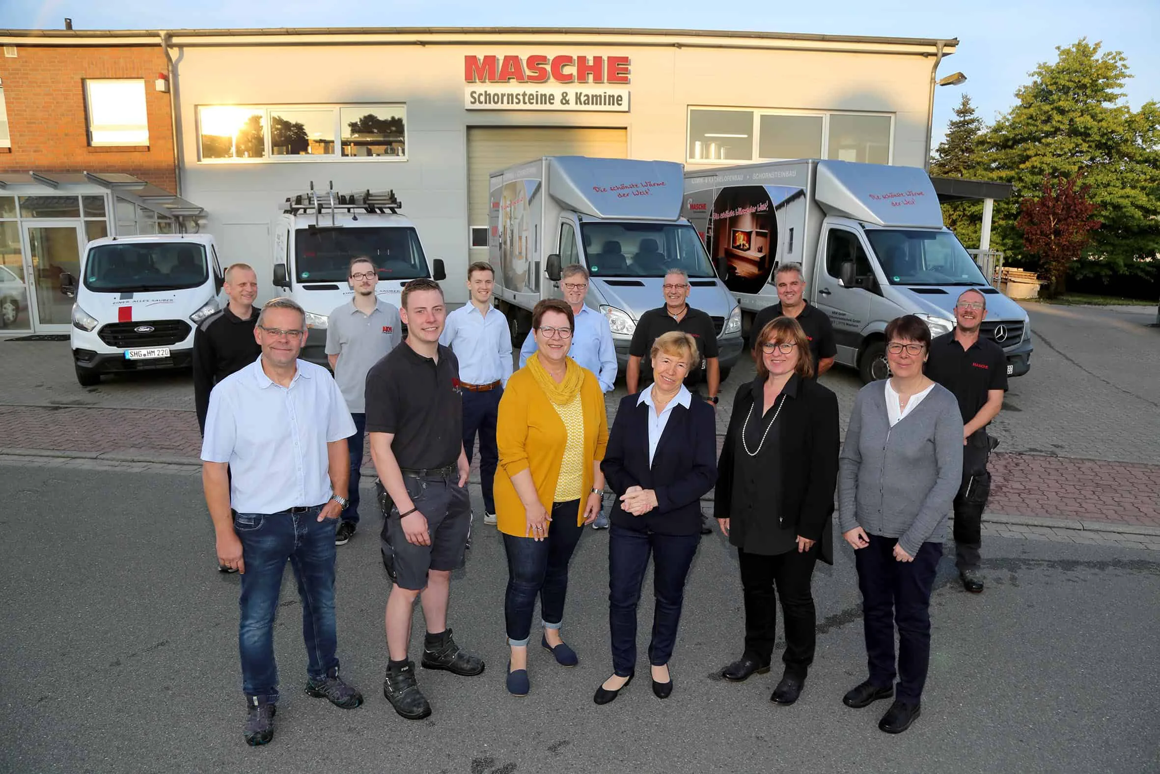 AKM Masche Team mit Geschäftsführer Holger Masche Mitarbeiterteam von AKM Masche mit Geschäftsführer Holger Masche vor Firmengebäude und Servicefahrzeugen in Meerbeck.
