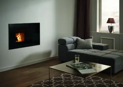 RIKA P INTERNO Pelletofen mit schwarzer Glasfront, wandbündigem Einbau und sichtbarem Feuer im Wohnraum.