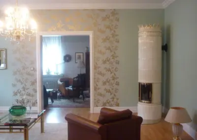 Klassischer Säulenofen mit heller Keramikverkleidung und schlanker, hoher Bauform in einem elegant eingerichteten Wohnraum.