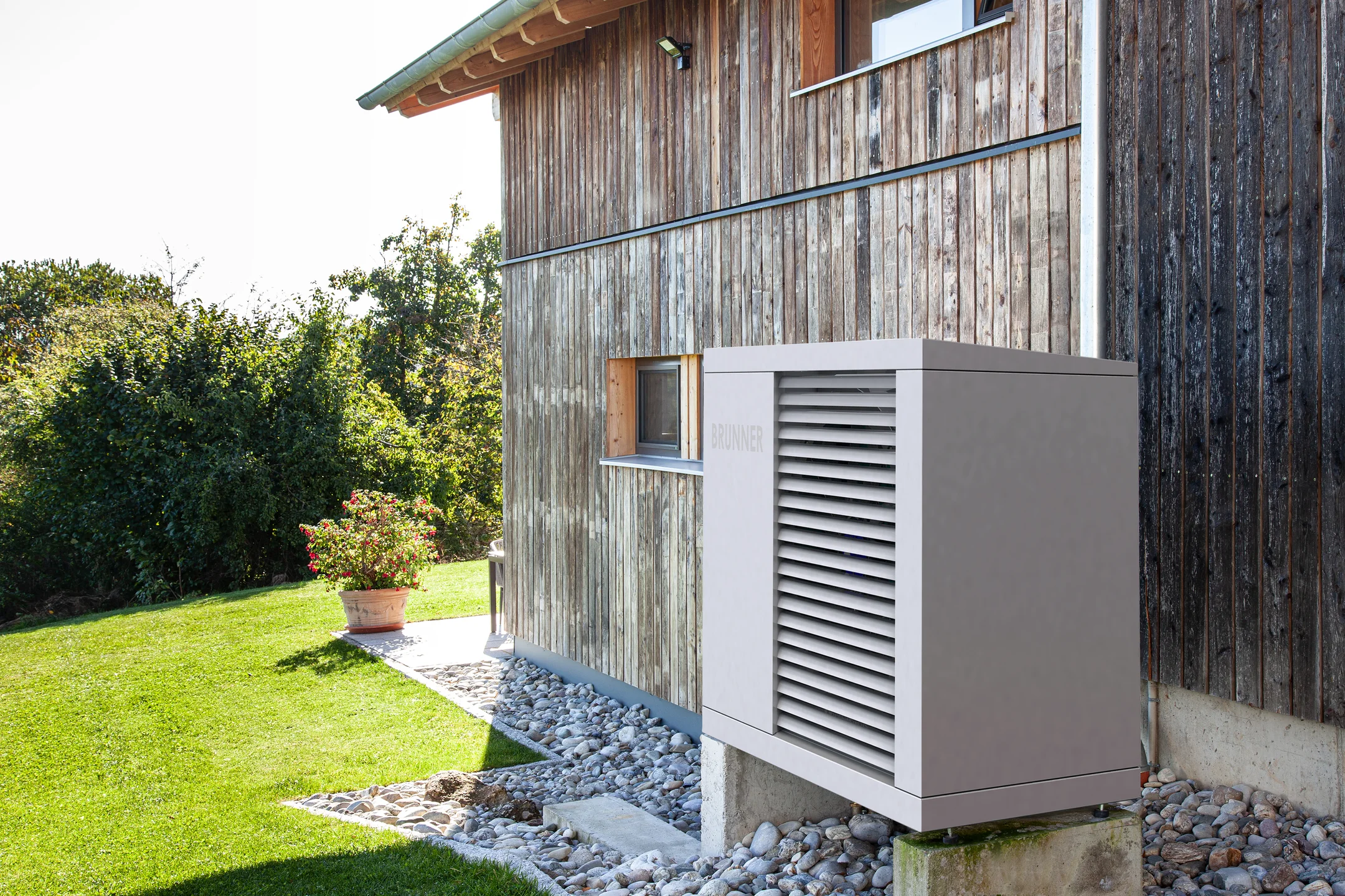 BRUNNER Wärmepumpe im Außenbereich, direkt an der Holzfassade eines Wohnhauses aufgestellt.